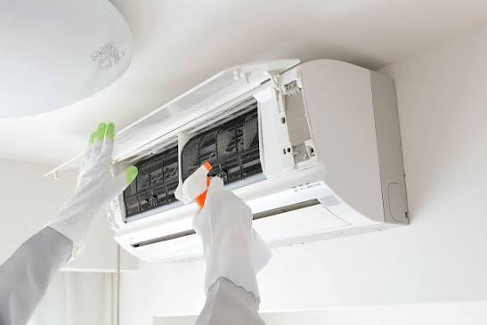 Technician cleaning and checking an air conditioner